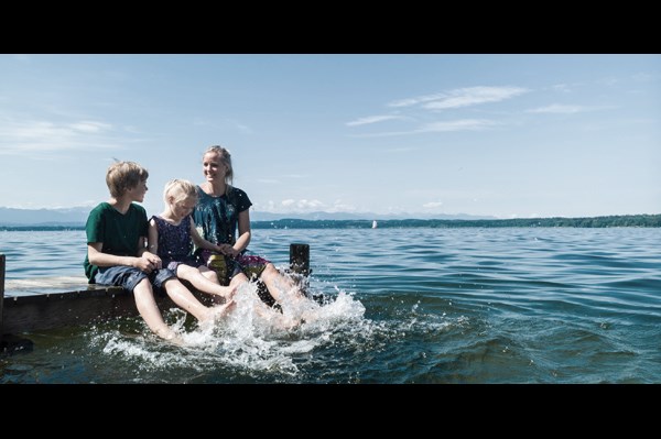 Familie sitter på brygga og plasker i vannet